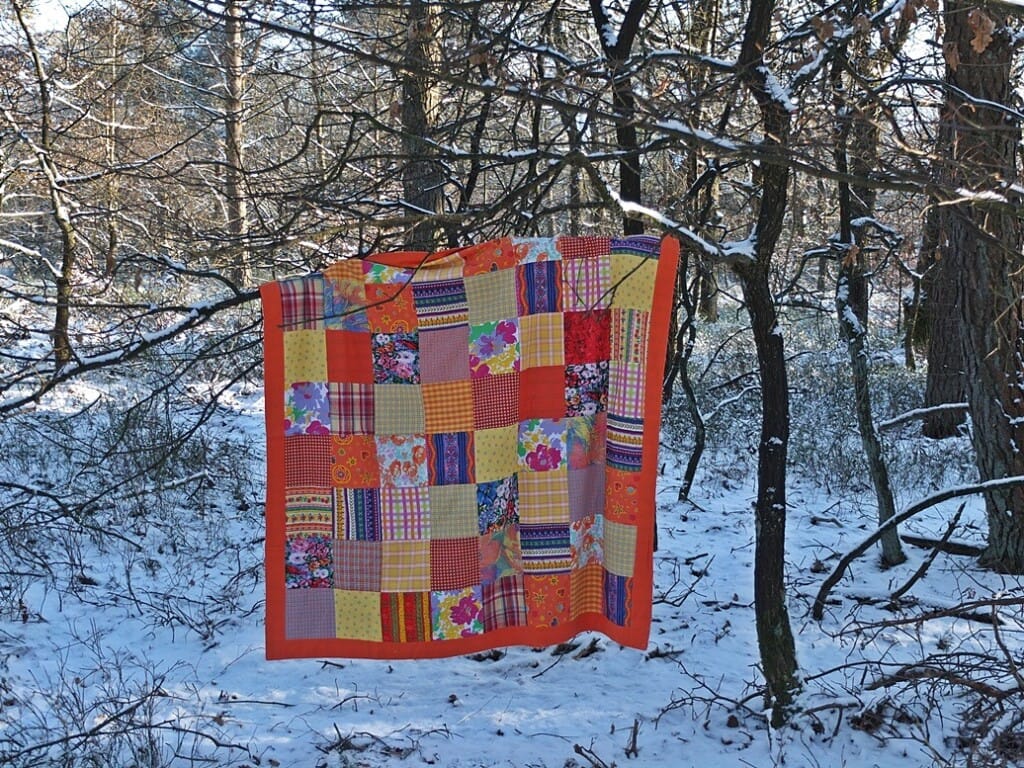Oranje quilt in besneeuwd bos