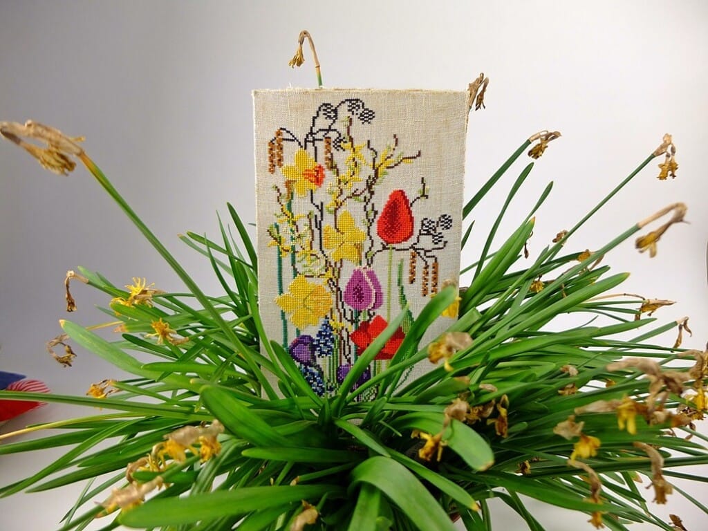 Borduurwerk voorjaarsbloemen tussen uitgebloeide narcissen