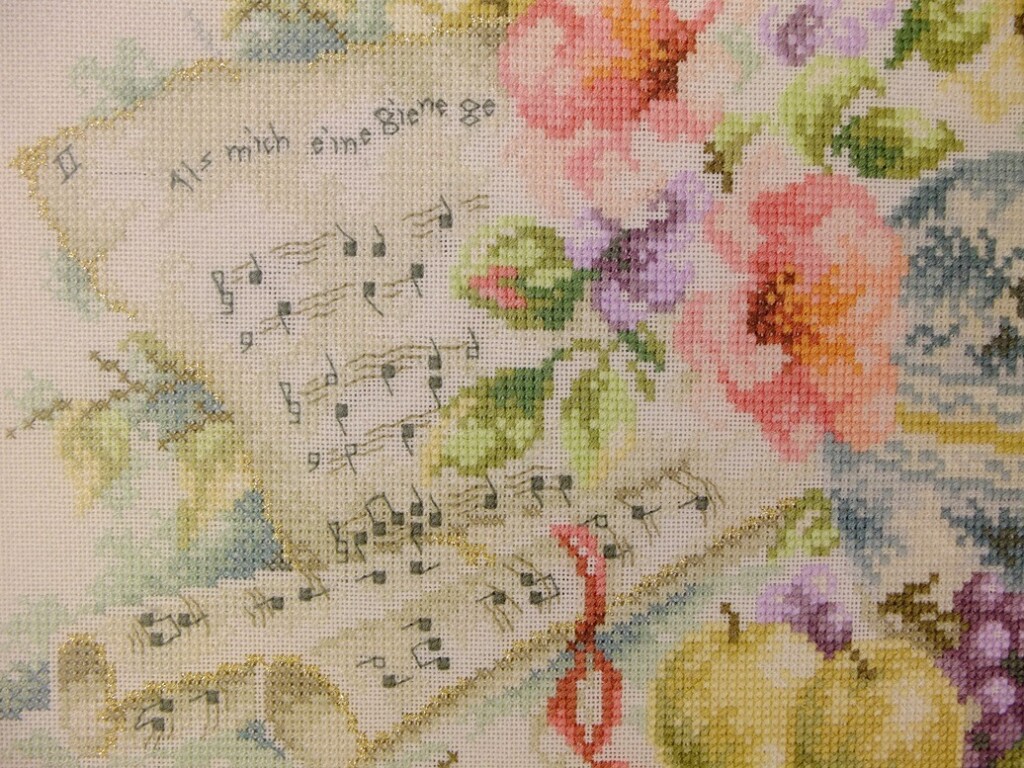 Detail geborduurd schilderij bladmuziek en bloemen