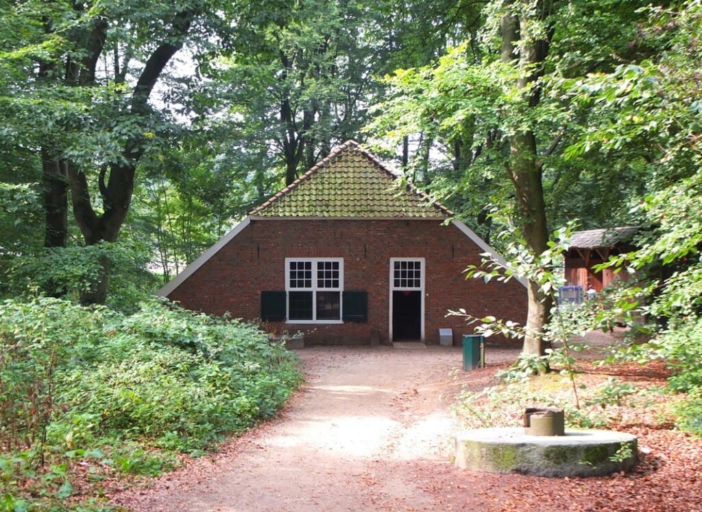 Klein boerderijtje tussen hoge bomen in Openluchtmuseum