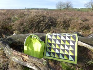 Groen quiltje en groene rugzak op hei