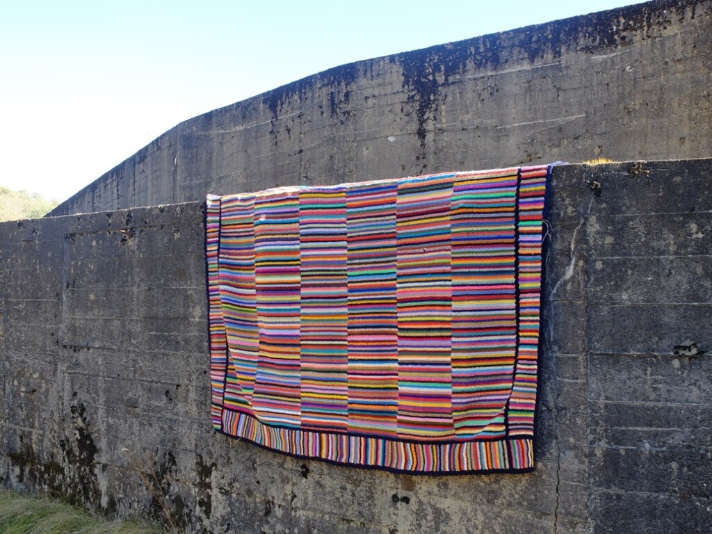 Gehaakte deken over grijze muur