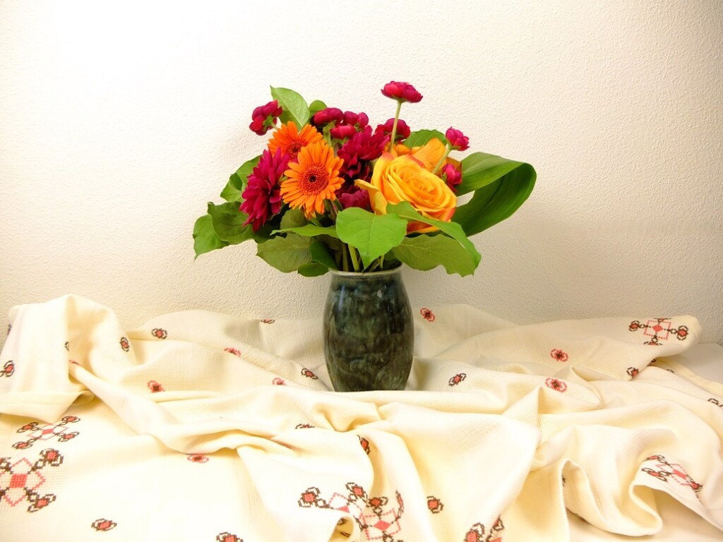 Vaas met bloemen op geborduurd tafelkleed